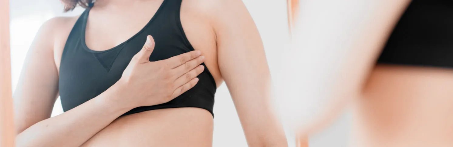 A woman considering breast augmentation as she looks in the mirror