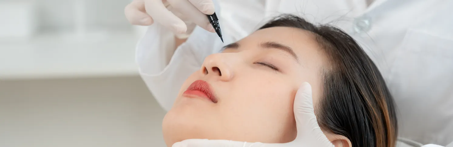 Plastic surgeon pointing a marker on a woman’s face