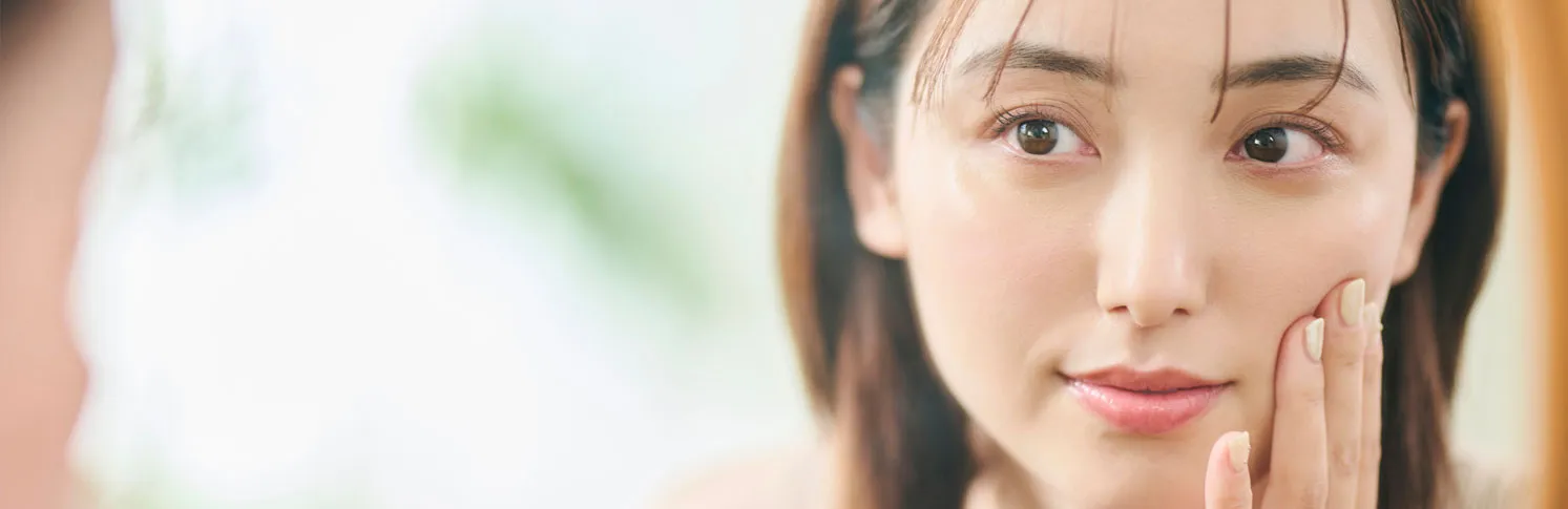 A woman considering plastic surgery while looking in the mirror